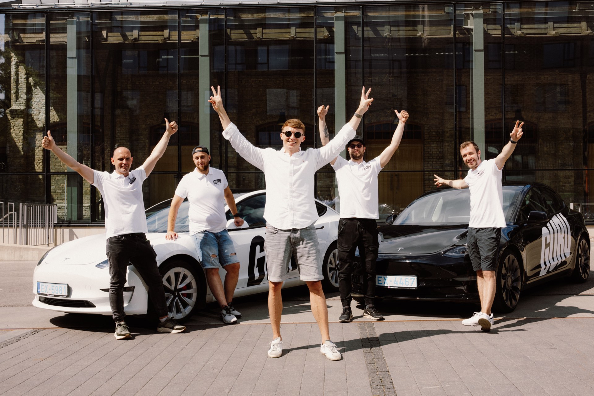 The GURU team celebrating in front of their Teslas